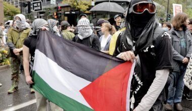 Masked protesters hold a Palestinian flag during a rally on the streets of Montreal on Oct. 7, 2025