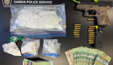Drugs, cash, bullets and a gun are neatly laid out on a black table
