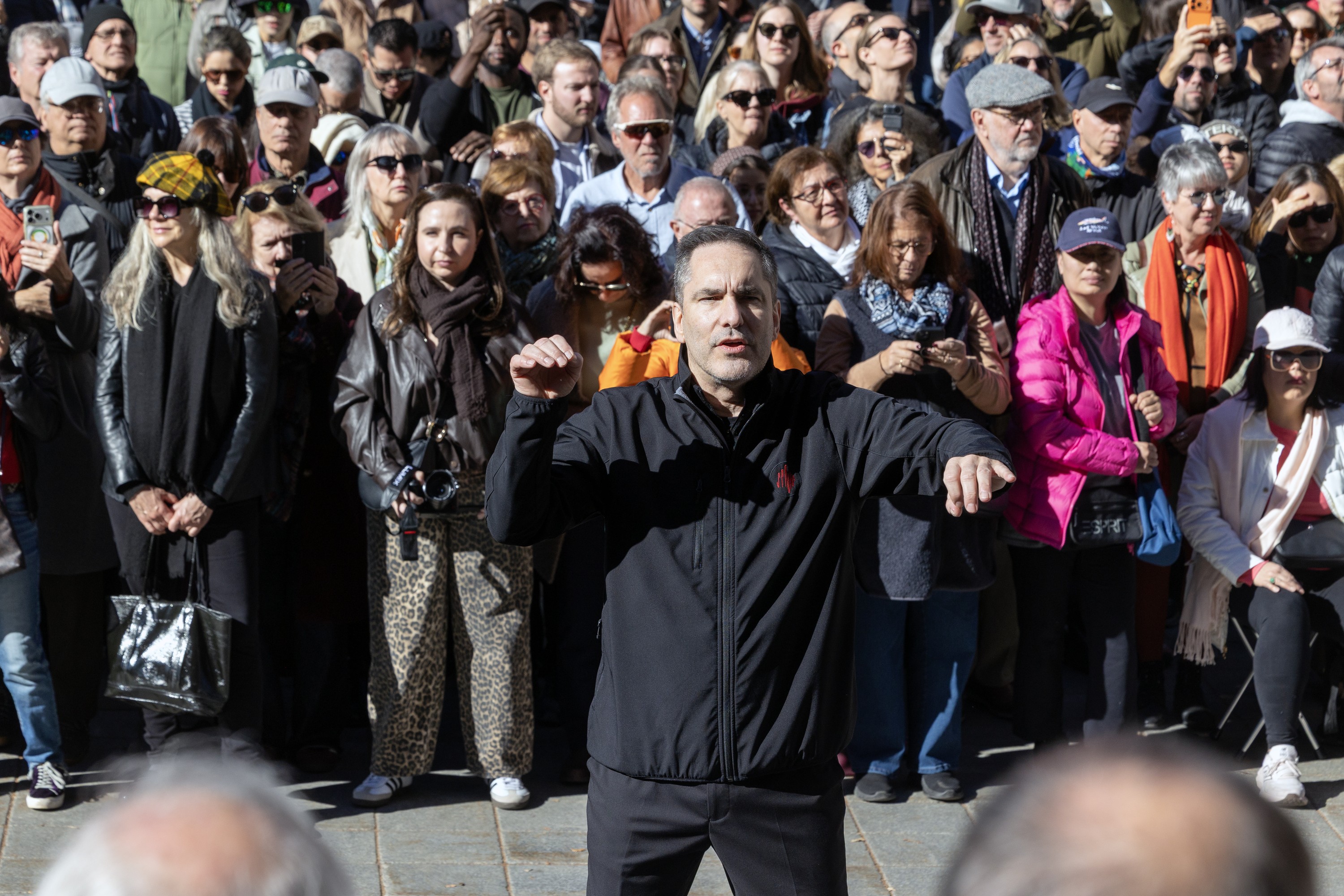 A crowd listens to a choir under the direction of Michel Brousseau during an event marking the unveiling of Notre-Dame Basilica's facade after years of restoration
