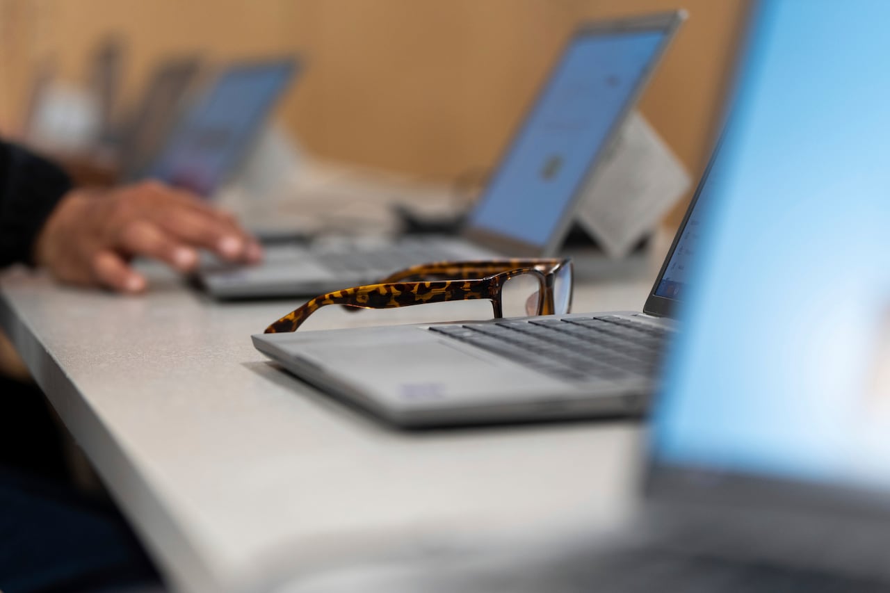 A pair of glasses sit next to a laptop.