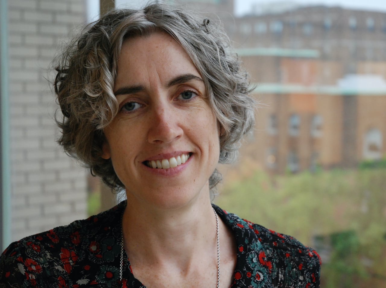 The photo is a head-and-shoulders profile image of a woman. She is smiling.