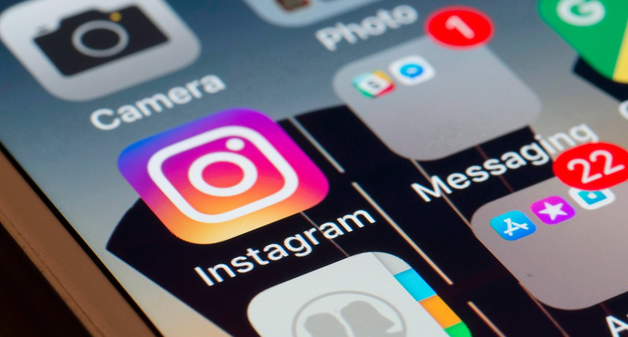 A phone screen with the apps visible is shown up close, with Instagram in view.