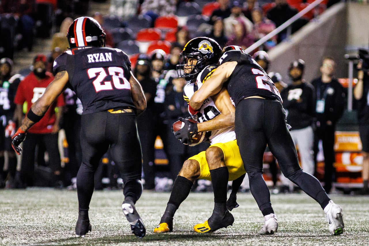 Football players are seen tackling each other mid-game.