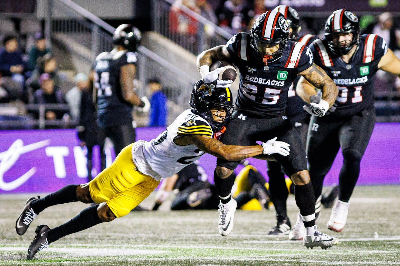Football players tackle each other mid-game.