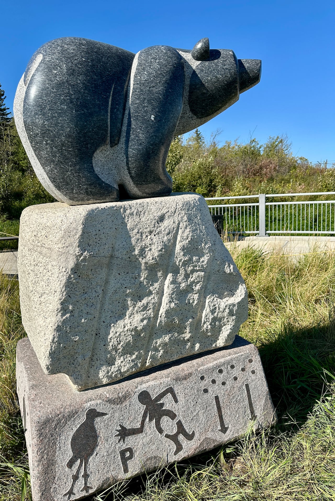 A stone sculpture of a bear against a blue sky