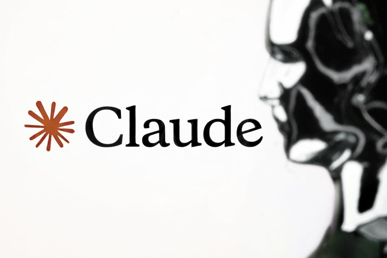 A silver robot profile is photographed against a white screen with black text and an orange symbol beside it.