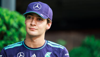 Mercedes F1 driver George Russell looking upwards, wearing a cap.