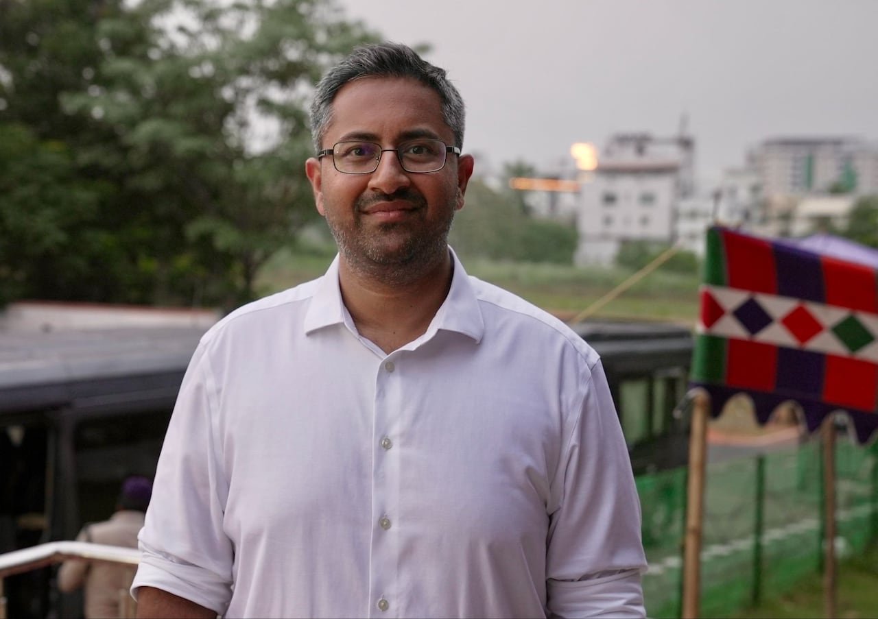A man with a light beard, in a white shirt and standing outdoors, poses for a photo.