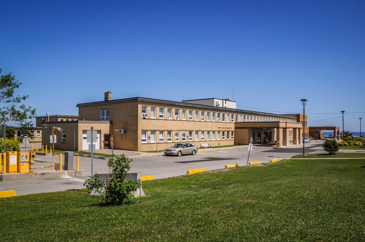 A two-storey hospital with surrounding grass and trees.