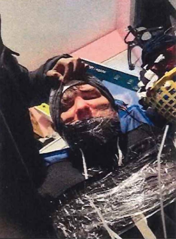 Man with mask taped to his face, body taped.