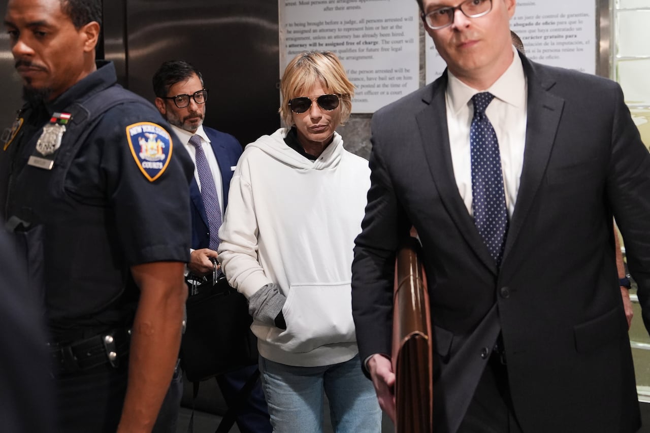 woman stands between two men leaving court in sunglasses and hoodie