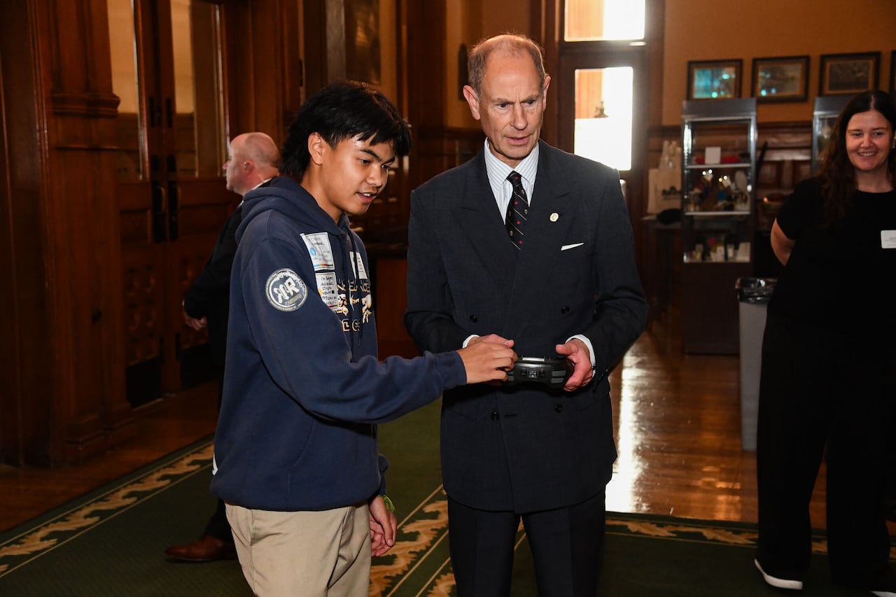 A teen and an adult hold a robotic controller.