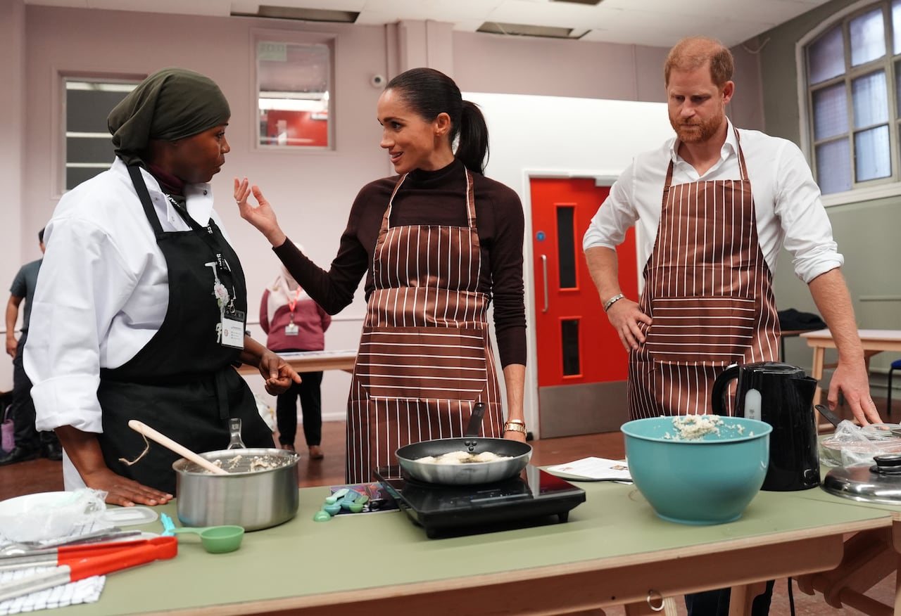 Three people stand in a kitchen.