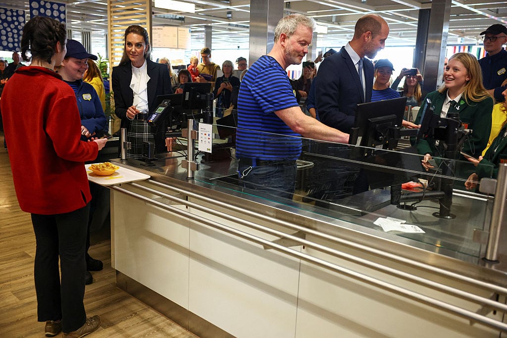Several people stand around a restaurant cash counter.