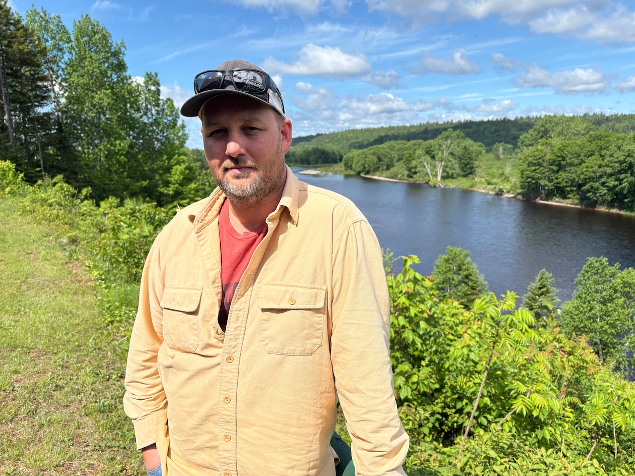 A man poses for the camera in front of a river.