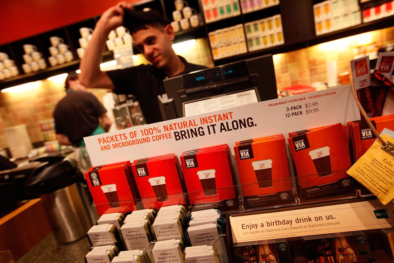 A Starbucks employee behind stock of instant coffee.