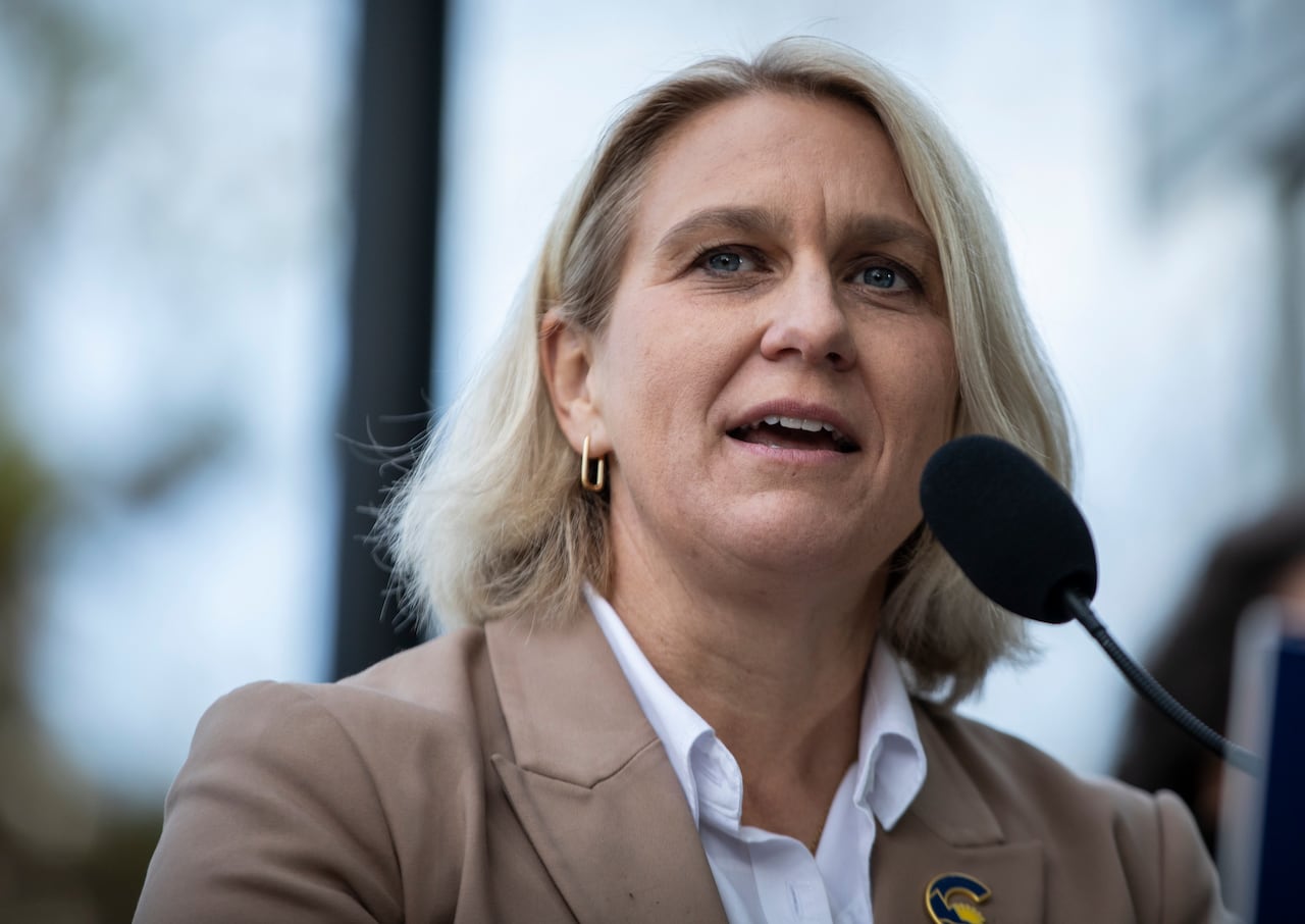 Elenore Sturko is seen in a beige coat speaking.