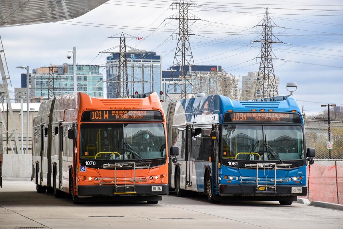 A red bus and a blue bus are in a bus station.