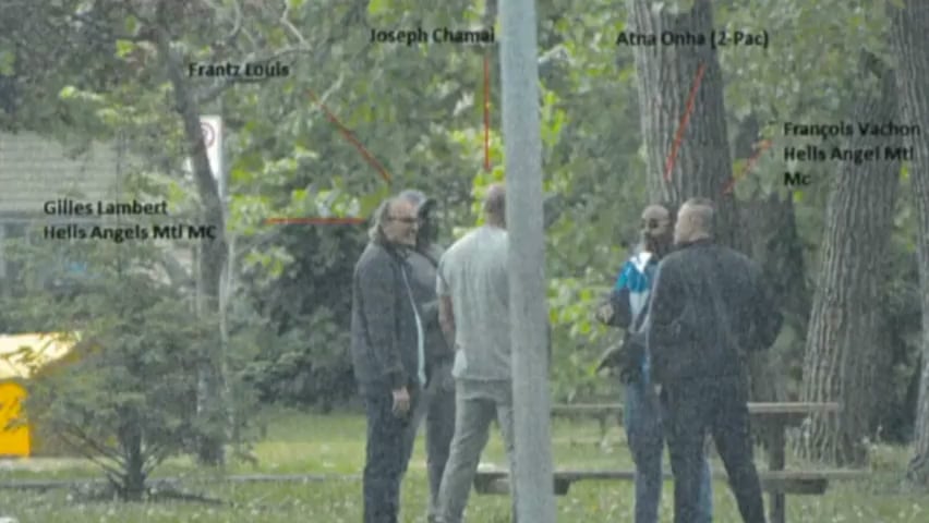 Five men standing in a circle in a wooded park