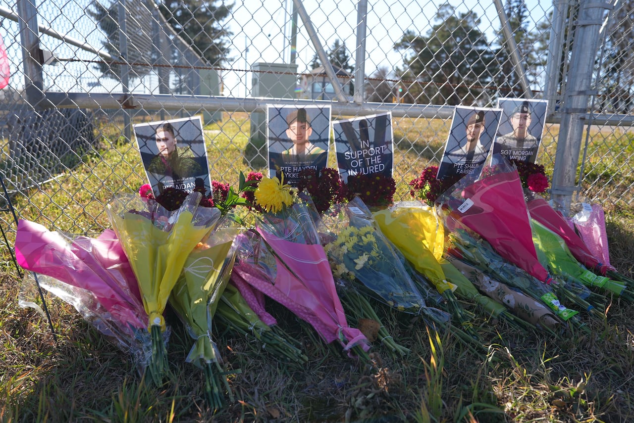 Flowers and other memorial markers are pictured along the fence near the front entrance of CFB Wainwright on October 20, 2026.