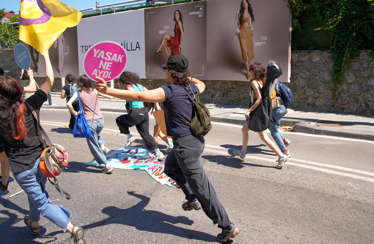 People holding banners and placards run down a city street.