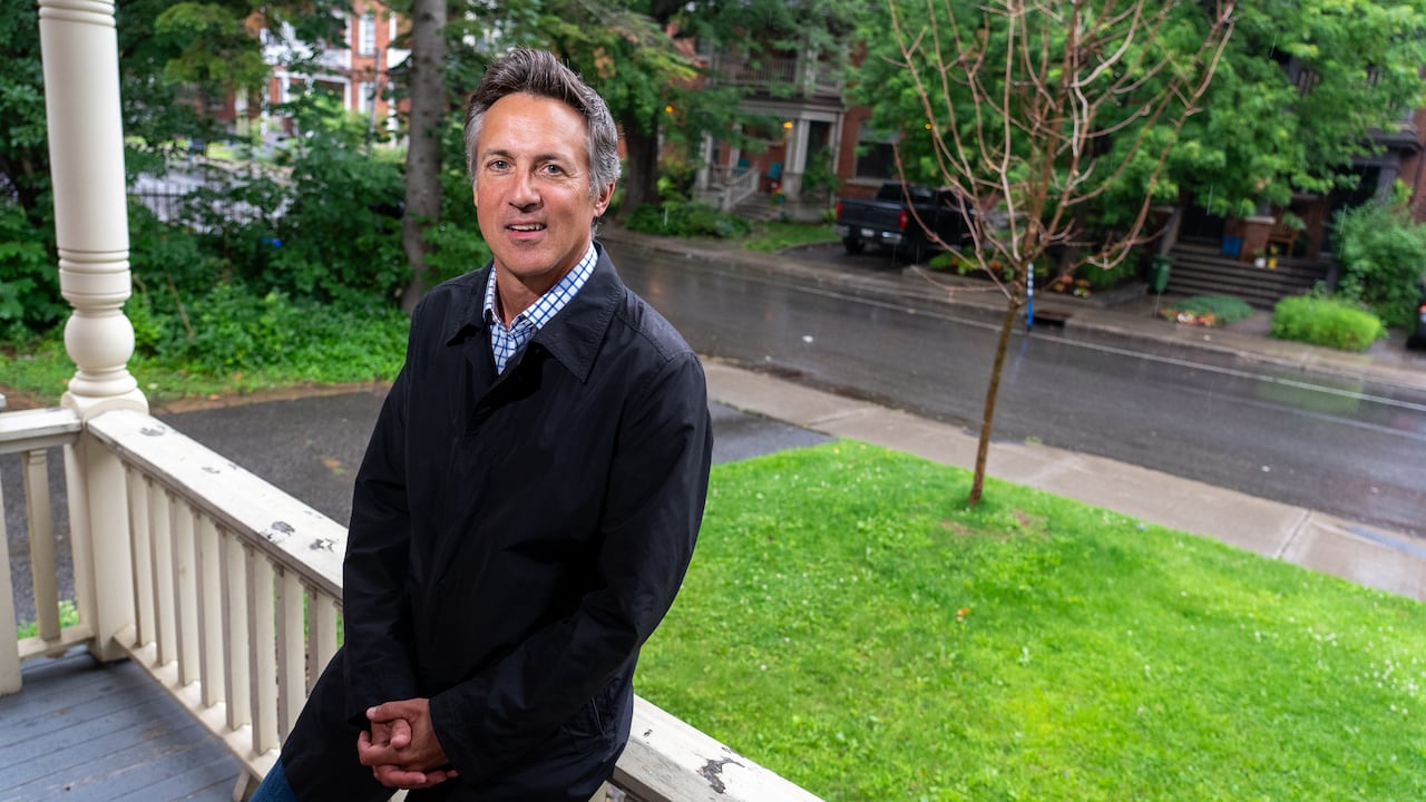 A man leans against a railing on a porch