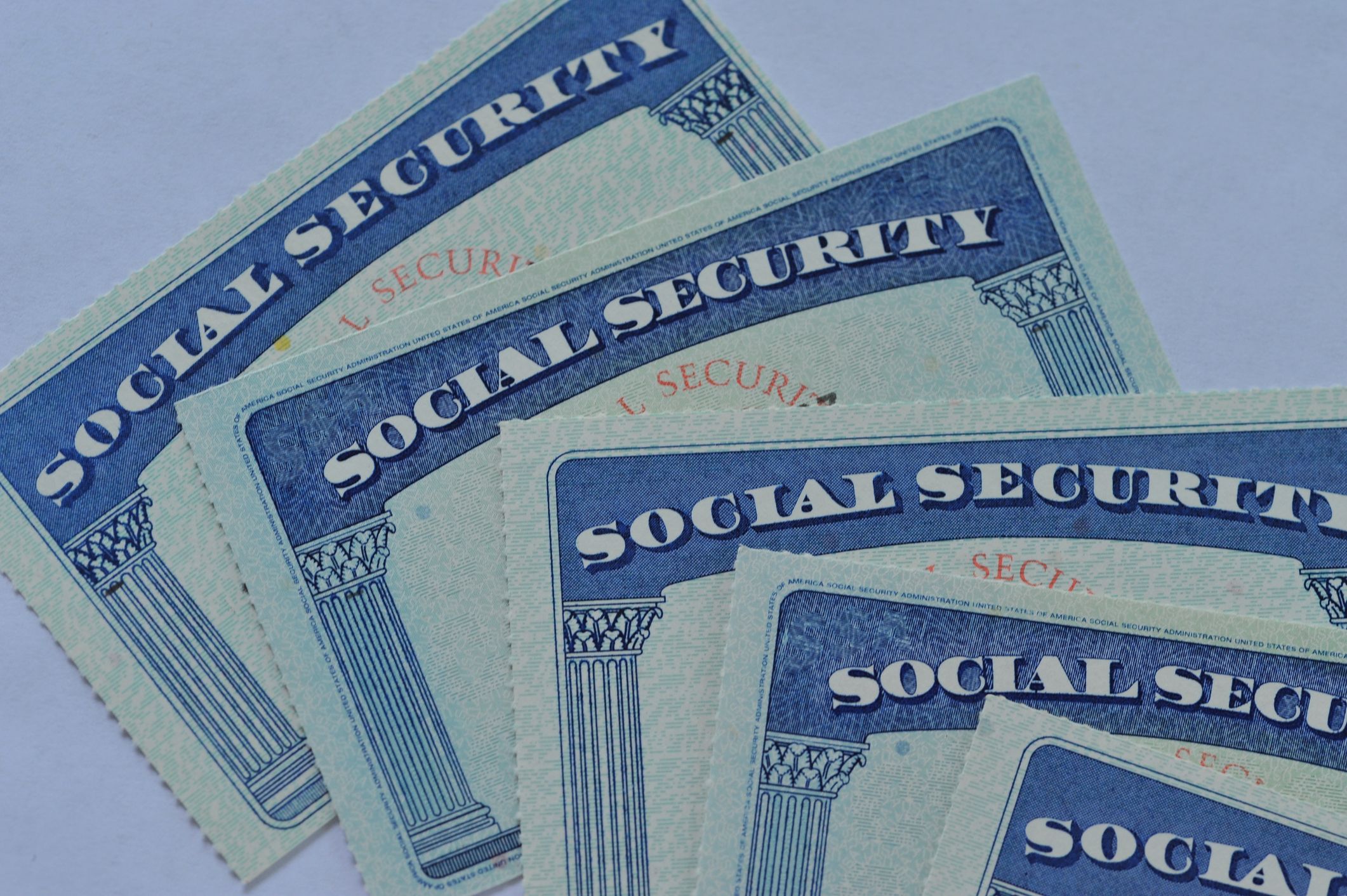 Several overlapping U.S. Social Security cards on a light background