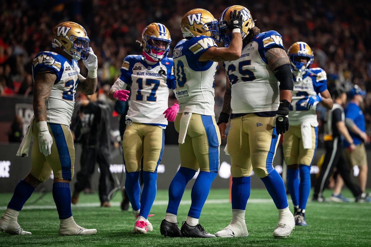 Football players in blue, gold and white uniforms gather together on a field