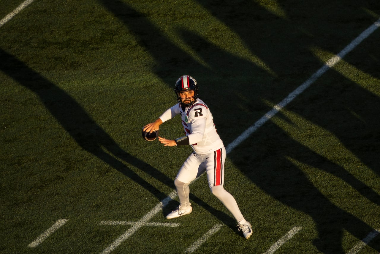 A quarterback is lit by late afternoon sunlight as he prepares to throw a pass.