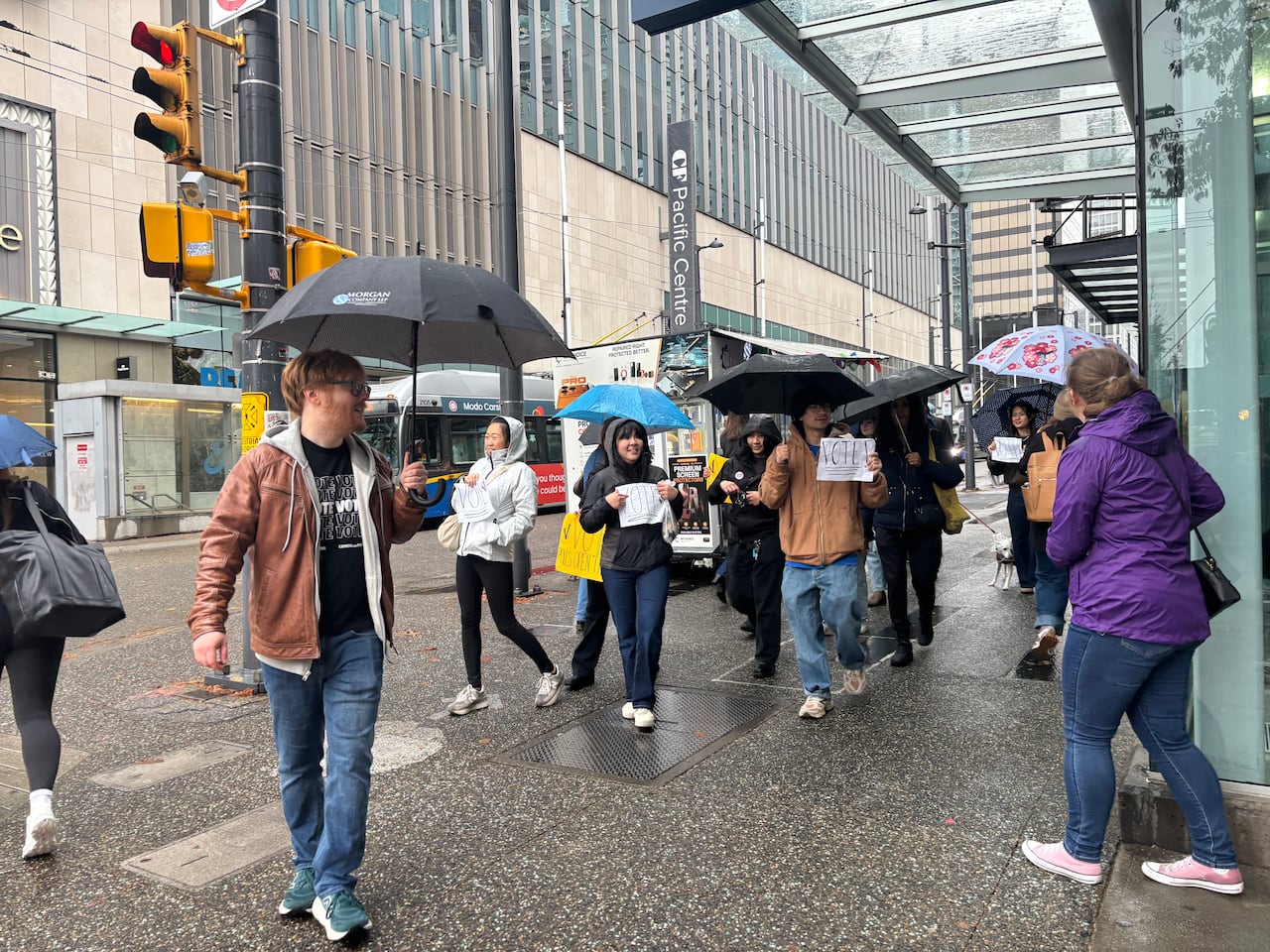 A group of people are pictured walking down the street holding signs that say "Vote."