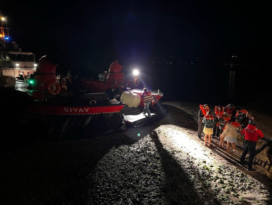 Students are pictured walking on terrain, boarding a hovercraft on amid a rescue.