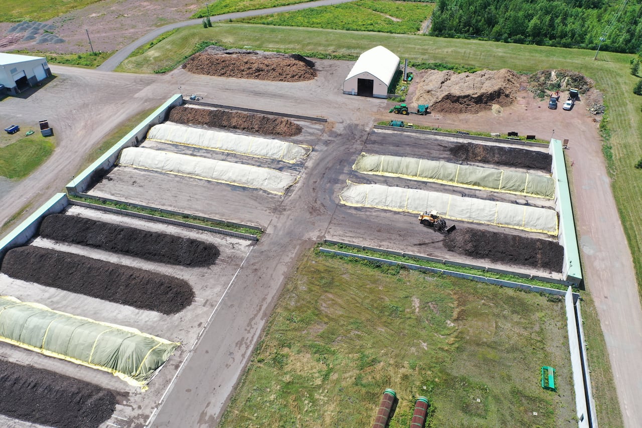 Rows of dark brown or black material, some covered by yellow tarps. 