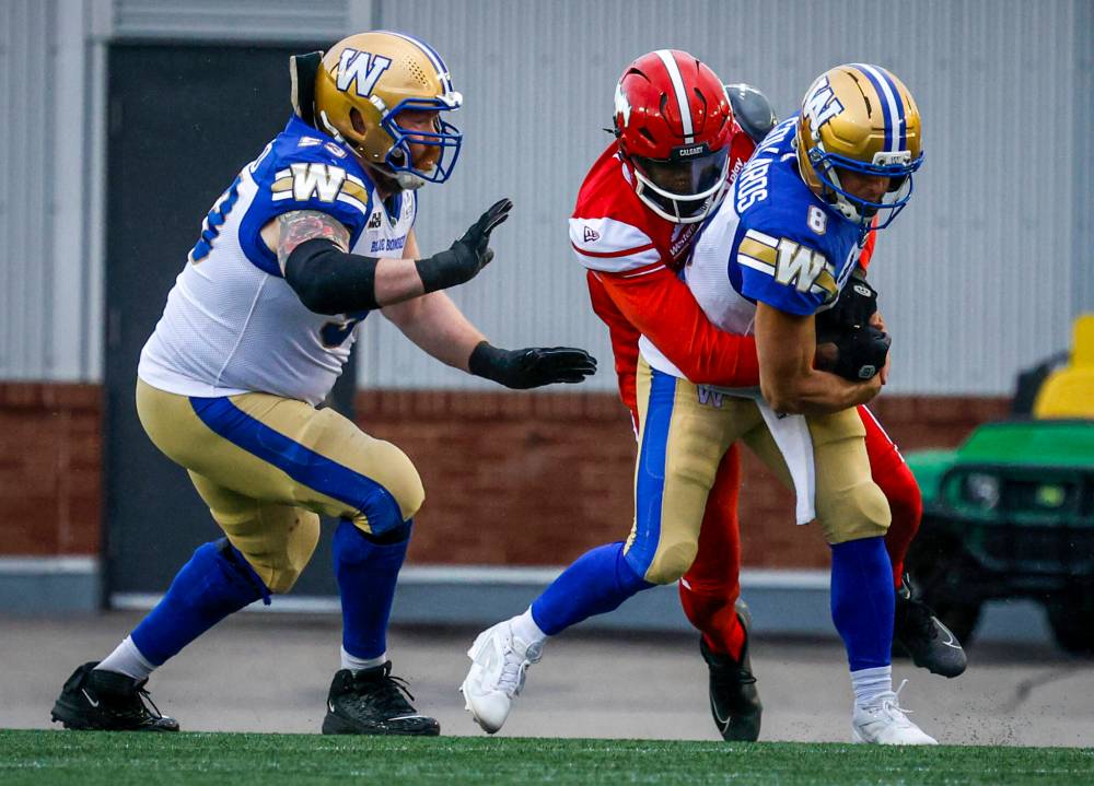 JEFF MCINTOSH / THE CANADIAN PRESS FILES
Winnipeg Blue Bombers quarterback Zach Collaros (right) is sacked by Calgary Stampeders defensive lineman Clarence Hicks (centre) back in June. Calgary’s star pass-rusher has already taken down Winnipeg quarterbacks twice this season and leads the CFL with 12 sacks.