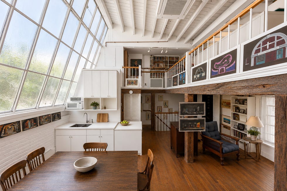 Bright, modern interior of an open-concept kitchen and living area with large windows and artistic decor.