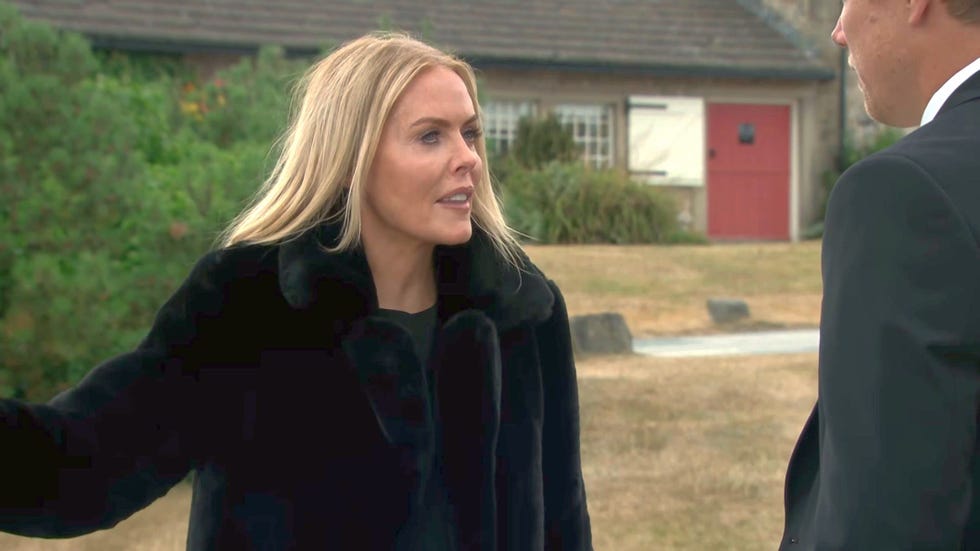 emmerdale, sadie king in a black coat speaking angrily to robert sugden, seen from behind in right side of frame