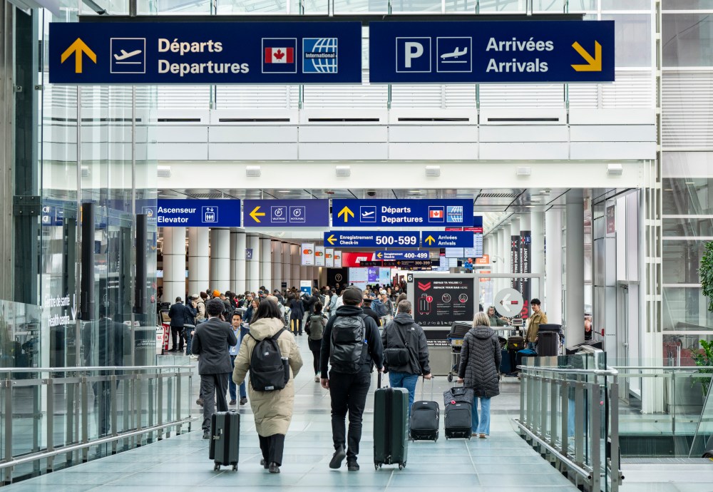 Travellers are seen walking towards Canadian departures at Montreal-Pierre Elliott Trudeau International Airport in Montreal on Wednesday, March 18, 2026. THE CANADIAN PRESS/Christinne Muschi