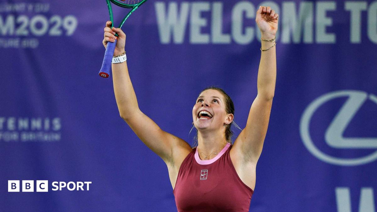 Hannah Klugman, in maroon tennis outfit, celebrates with both arms aloft as she looks upwards