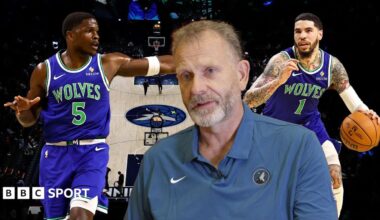 Tim Lewis with Anthony Edwards and LaMelo Ball behind him in front of the basketball court at the Target Centre
