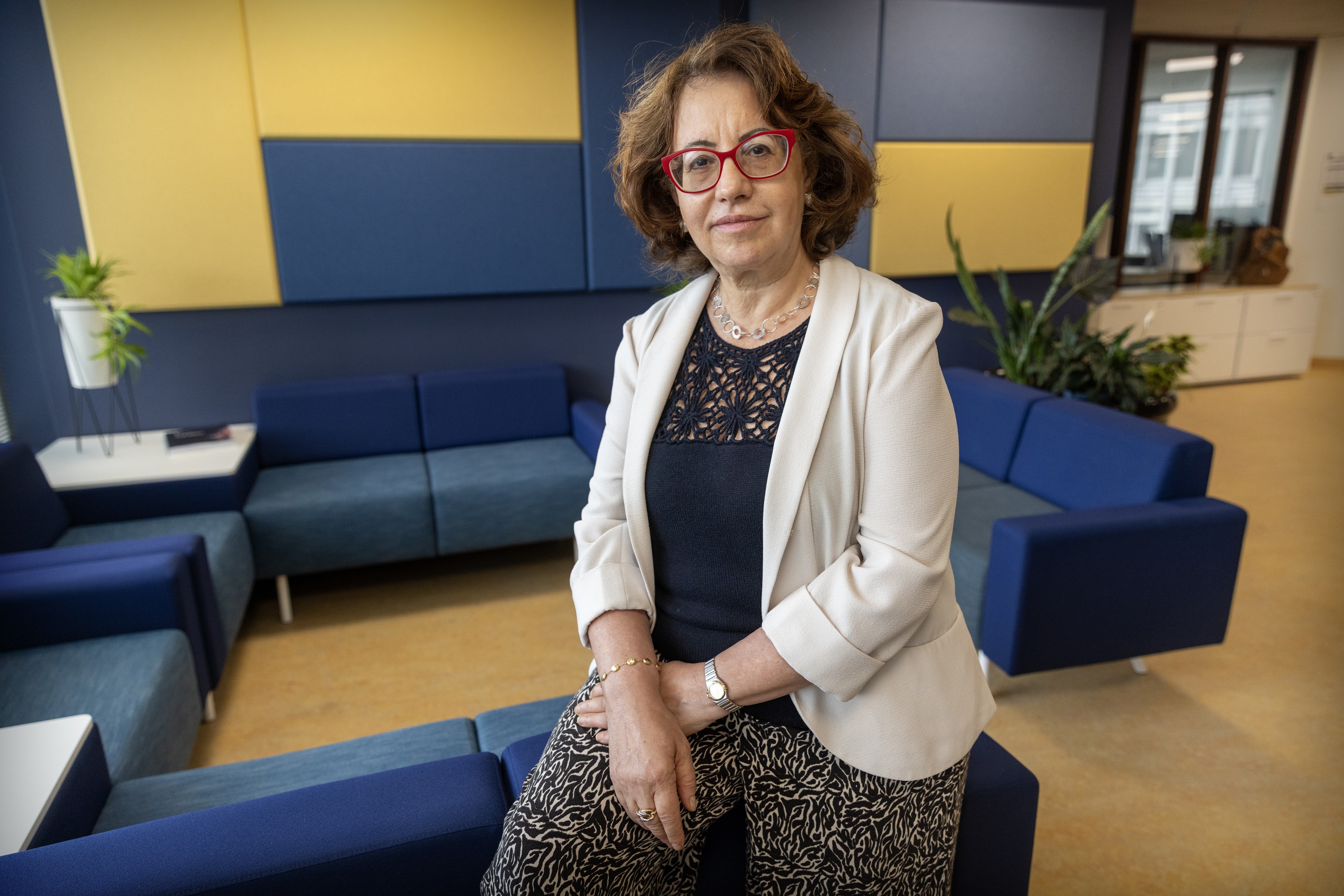 A woman in a comfortable waiting area leans on one of the blue sofas.