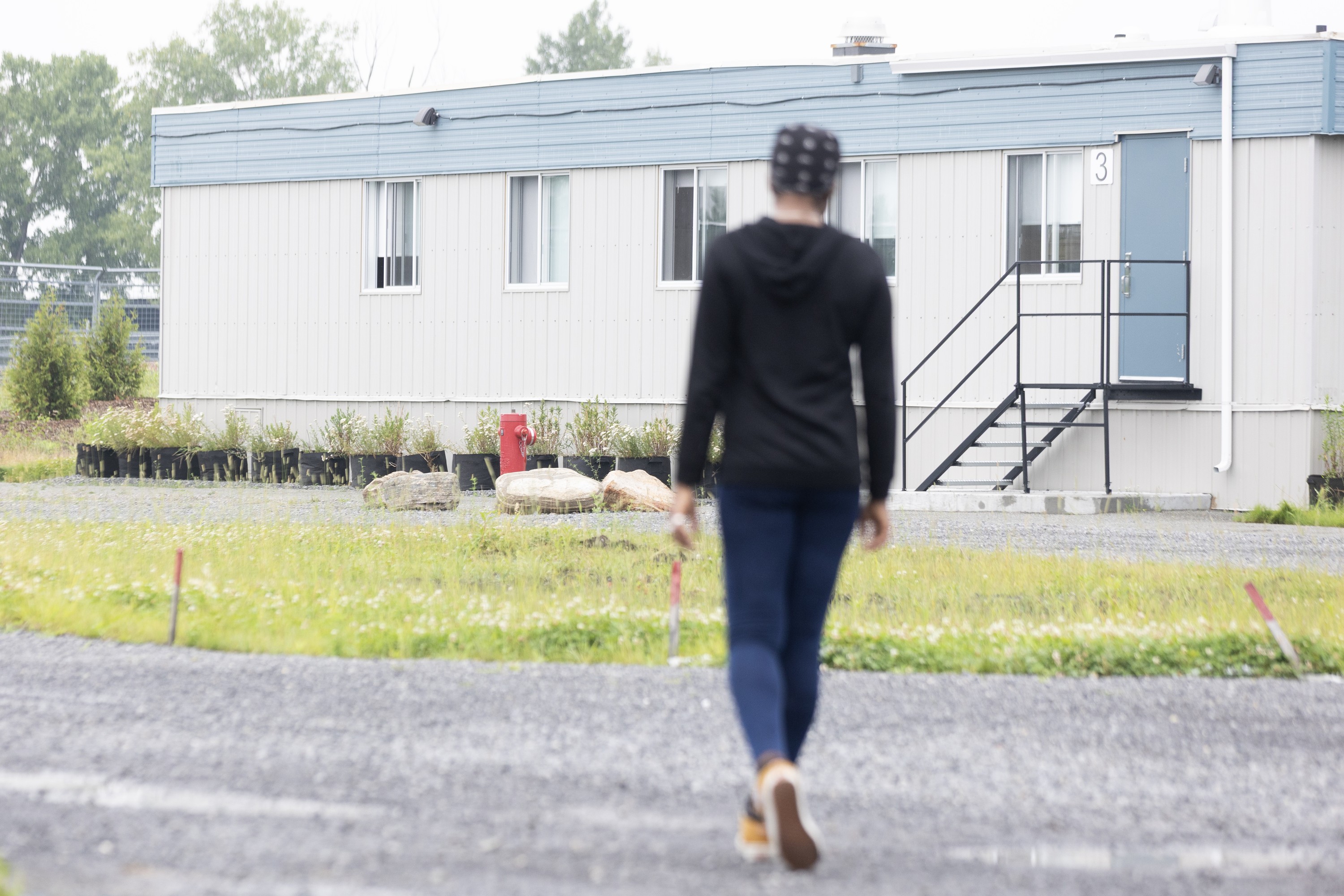 A woman walks toward a modular housing unit.