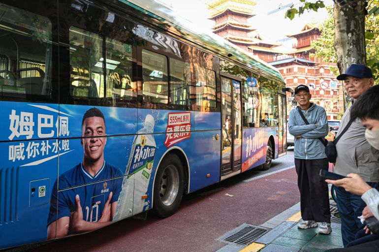 A bus featuring French football star Kylian Mbappe for Dongpeng Beverage Group's "Bushuila" electrolyte drink is seen on a street in Shanghai on October 27, 2026. Kylian Mbappe was dropped on October 27 by two major brands in China after a video circulated online in which the French football star apparently joked about former leader Mao Zedong. (Photo by Jade GAO / AFP)
