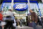 Passers-by walk in front of a Boots Store on Oxford Street in London.