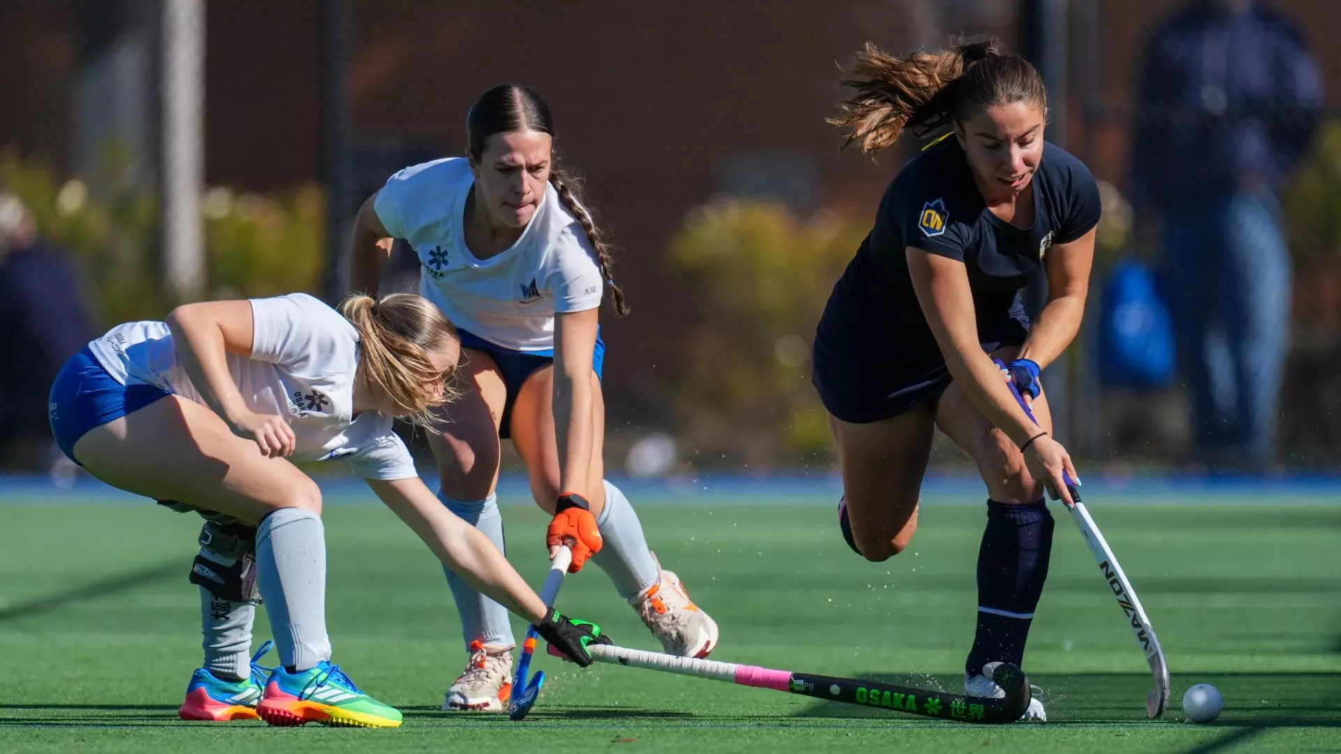 A UBC T-Bird avoids an outstretched poke attempt by a defender while another trails just behind near the sideline during a game against the UVic Vikes on Sept. 27, 2026