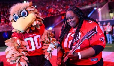 Diamond Rowe playing guitar next to a man dressed as a giant falcon