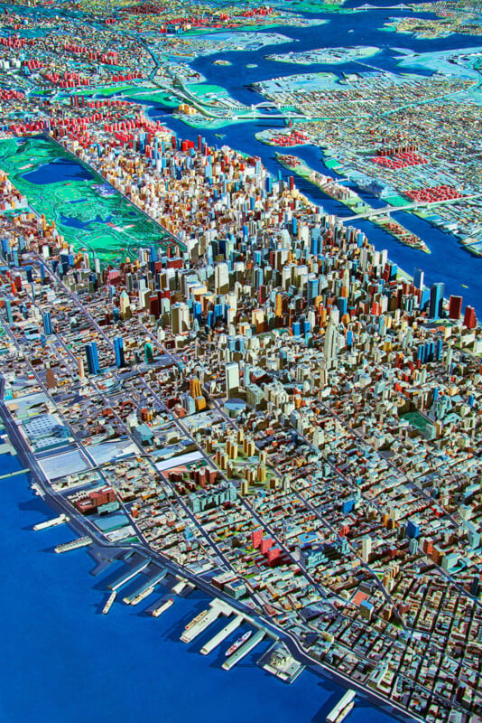 An aerial view of a detailed architectural scale model of Manhattan, featuring Central Park, the surrounding skyscrapers, and the adjacent rivers.