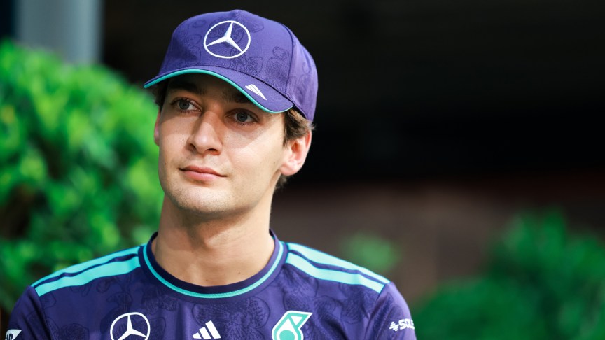 Mercedes F1 driver George Russell looking upwards, wearing a cap.