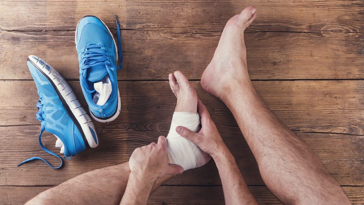 Injured runner sitting on a wooden floor background