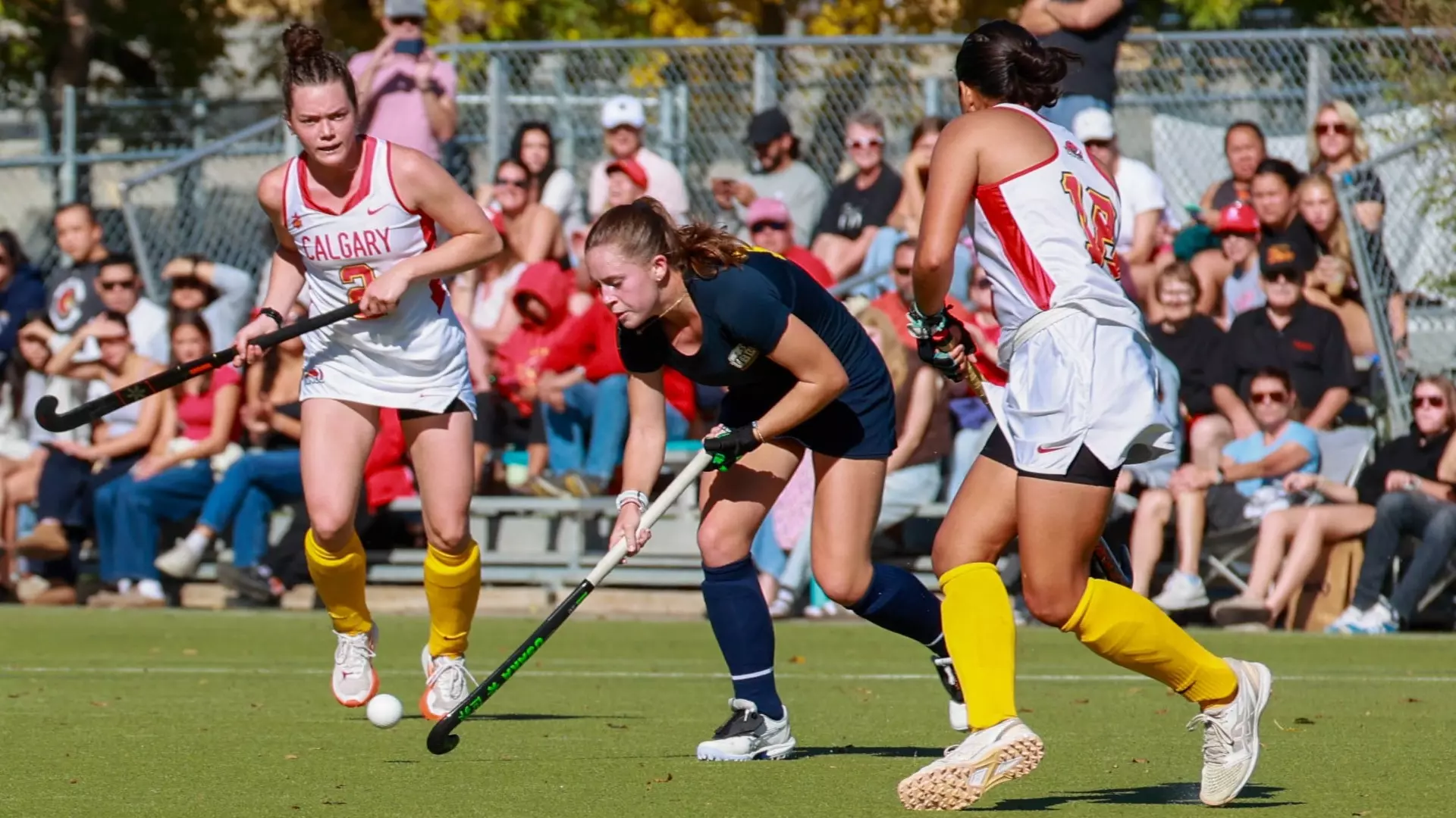 A T-Bird with the ball tries to the avoid a pair of incoming defenders during a game against the University of Calgary Dinos on Sep. 20, 2026