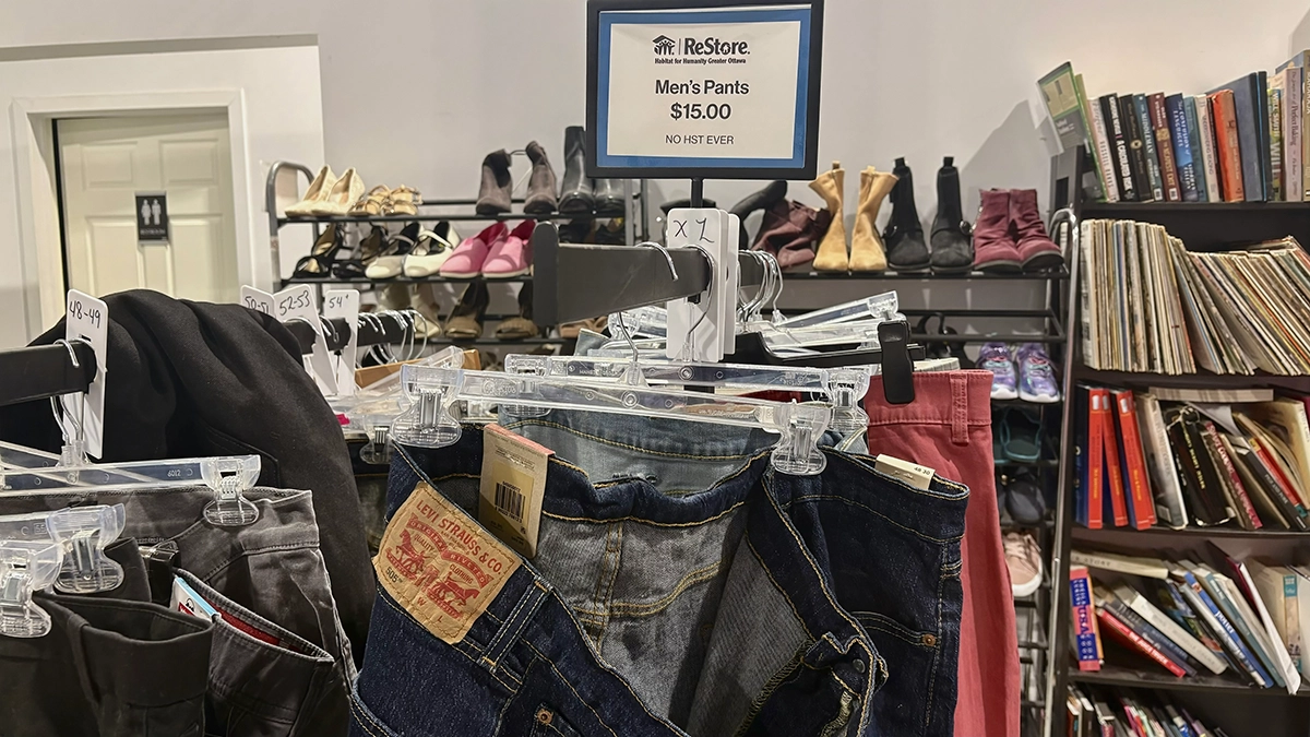 A pair of Levi's jeans hangs on a clothing rack at a Habitat for Humanity ReStore in Ottawa, beneath a sign advertising men's pants for $15.