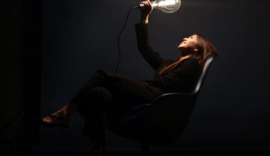 Tina Yao in black suit holding a glowing light bulb